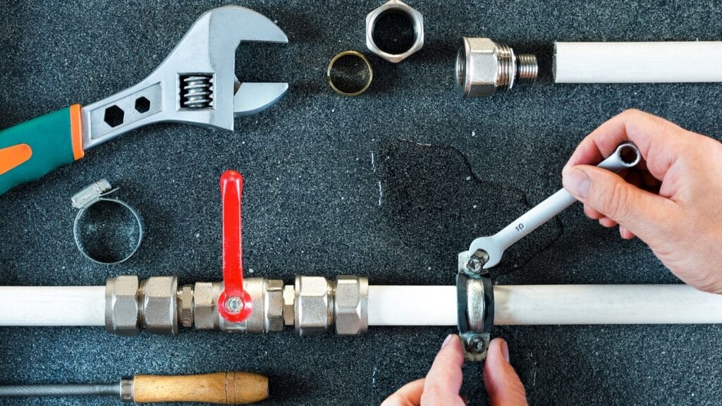 Plumber repairing a pipe valve with an adjustable wrench in Thornton