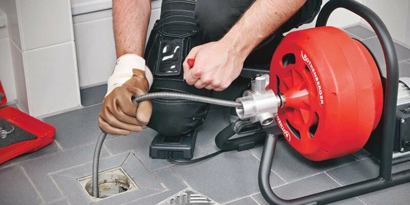 Plumber using a drain-cleaning machine in Thornton