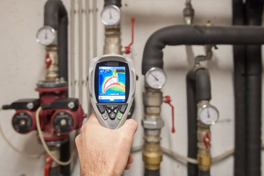 Plumber using a thermal imaging camera to inspect pipes in Thornton