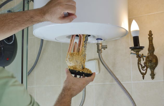 Technician removing mineral buildup from a water heater in Thornton