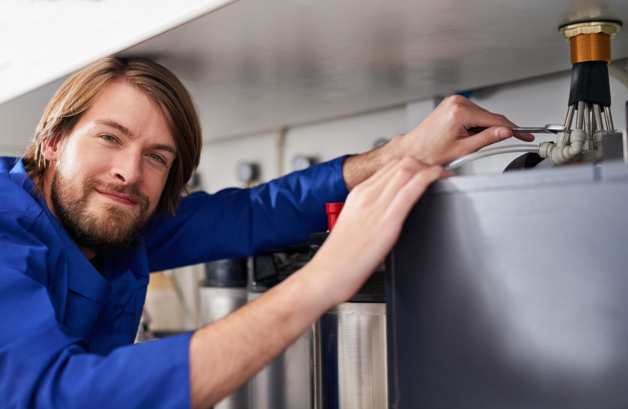 Technician servicing a residential water heater tank in Thornton