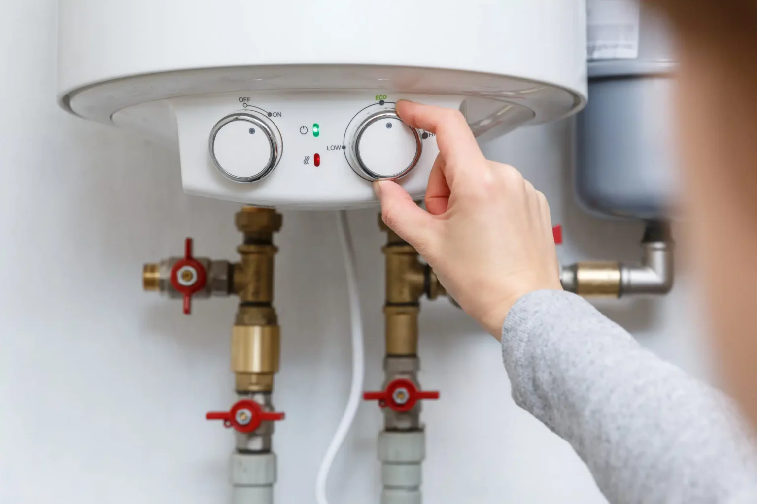 Homeowner adjusting the temperature controls on a water heater in Thornton